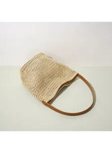 Woven beach bucket bag detail, straw material with brown leather shoulder strap, summer style.