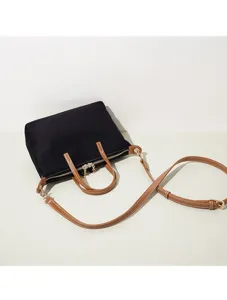 Borsa a tracolla in tela nera con manici in pelle marrone per un look quotidiano.
