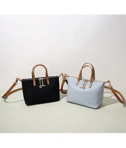 Dettaglio della borsa a tracolla casual con manici marroni e decorazione a catena.
