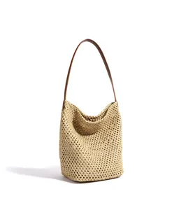 Woven straw bucket bag with brown leather shoulder strap, detailed view for summer beach.