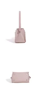 Detailed view of pink leather bucket bag bottom with metal protective feet and strap hardware.