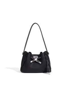 Black leather bucket shoulder bag detail, elegant metal turn-lock clasp and cross strap design.