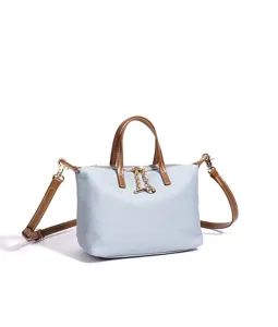 Dettaglio borsa in tela azzurra, manici in pelle marrone, ciondolo con zip dorata.