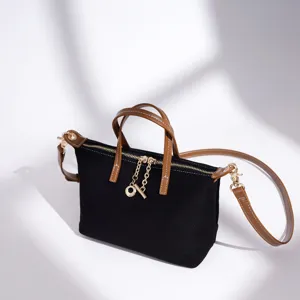 Borsa a tracolla in tela nera con manici in pelle marrone e dettagli dorati vista principale