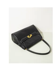 Vue détaillée d'un sac à main en cuir noir avec ferrures dorées et surpiqûres.
