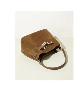 Detailed view of the brown suede bucket bag featuring chic metallic turn-lock and strap.