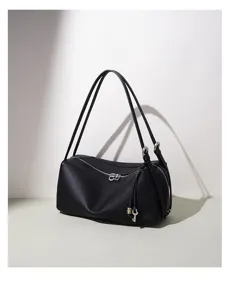 Detailaufnahme der minimalistischen schwarzen Ledertasche mit doppelten Trägern und Anhänger.