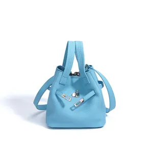 Detailed view of the light blue leather bucket bag featuring metal lock and dual top handles.