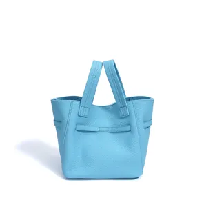 Light blue leather bucket bag detail showing soft pebble grain and sturdy handles.