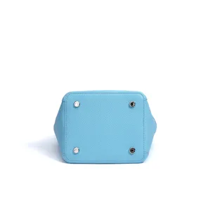Detailed bottom view of light blue leather bucket bag with metal feet, clean studio shot.