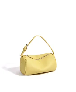 Vue détaillée du sac cylindrique jaune en cuir véritable, montrant la texture fine.