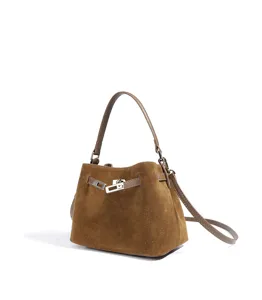 Detailed view of the brown suede bucket bag featuring metallic lock closure and elegant strap design.