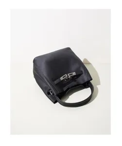 Black leather bucket bag detail showing premium texture and secure metal lock closure.