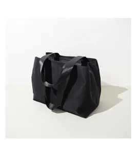 Close up view of the black nylon tote bag strap and fabric detail, showing minimalist design.