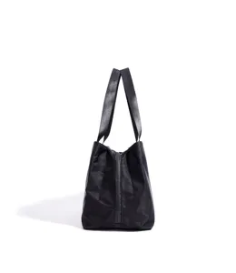 Black nylon tote bag close up, side view showing durable fabric handles and zipper detail.