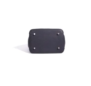Genuine leather bucket bag bottom detail showing four metal protective feet in black.