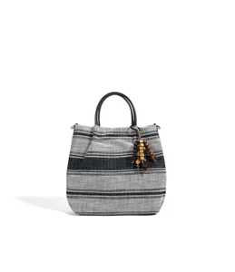 Detailansicht der schwarz-weißen Canvas-Handtasche mit ethnischen Holzperlen-Anhängern.