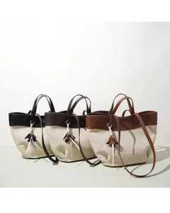 Detailed view of the stylish canvas and leather tote bag featuring a chic tassel charm and trim.