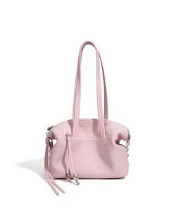 Detalle de bolso de hombro en cuero rosa con textura suave, doble asa y elegante colgante de llave.