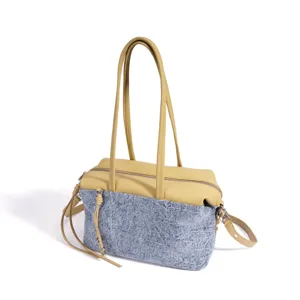 Vue détaillée du sac bandoulière en cuir et denim avec de longues anses et une fermeture éclair.