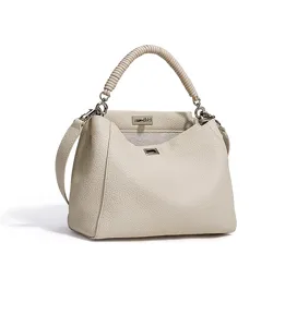 Elegante bolso de mano de cuero beige con asa envuelta con estilo y cierre metálico.