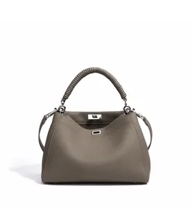 Vista detallada del lujoso bolso de cuero gris, elegante asa superior y diseño cruzado.