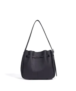 Detalle de bolso cubo bandolera de cuero negro, diseño retro vintage con hebilla metálica.