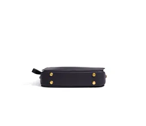 Vue détaillée du fond du sac à main en cuir noir avec quatre pieds en métal doré.