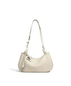 Gros plan détail du sac porté épaule croissant élégant avec breloque clé et cuir souple.