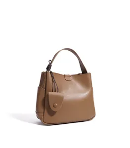 Brown leather bucket bag with top handle and chic knotted string detail, ideal for daily commute.