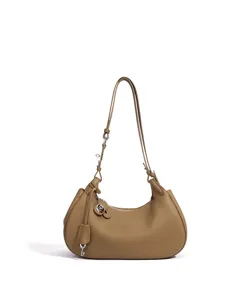 Vue détaillée du sac porté épaule croissant en cuir marron, texture fine et charm clé.