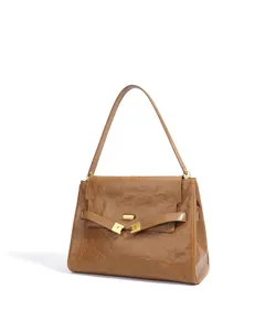 Vue détaillée du sac à main en cuir marron texturé avec fermoir en métal doré et bandoulière.