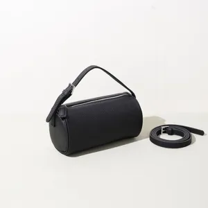 Sac à épaule cylindrique minimaliste en cuir noir, sac baguette élégant avec lanière.