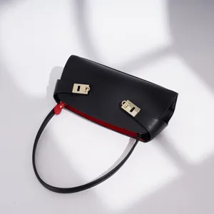 Elegante schwarze Leder-Achseltasche mit goldenen Verschlüssen und rotem Innenfutter.
