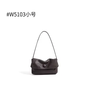 Dark brown leather shoulder bag detail, soft slouchy texture with single strap and flap.