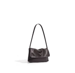 Close-up detail of brown leather shoulder bag, minimalist flap and slim strap style.