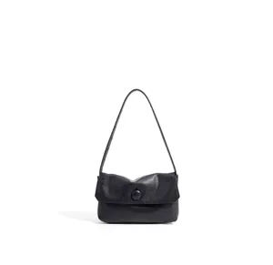 Close-up detail of the black leather shoulder bag flap and button accent, fine texture.