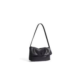 Close-up of minimalist black genuine leather shoulder bag with chic flap and button detail.