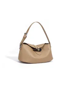 Detalle del bolso de hombro de cuero granulado, correa ajustable y cierre de palanca elegante.