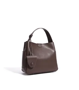 Dark brown leather bucket bag detail, featuring minimalist top handle and knot decoration.