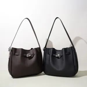 Elegante bolso de hombro tipo cubo de cuero genuino con diseño de correa y cierre giratorio.