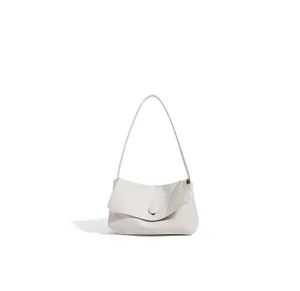 Close-up detail of white leather shoulder bag, minimalist flap design and compact shape.
