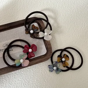 Detail shot of elegant acetate flower hair ties featuring delicate pearl centers and elastic bands.
