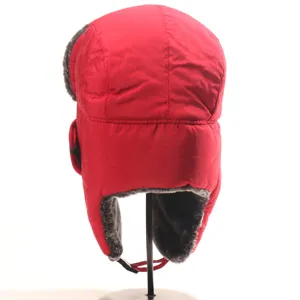 Close-up detail of the red winter bomber hat showing warm plush earflaps and fabric.