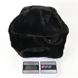 Detail shot showing a black faux rabbit fur ushanka bomber hat being weighed on a scale.