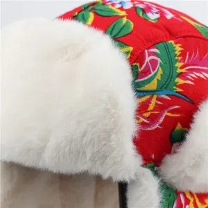 Close-up detail of winter warm bomber hat with floral print and white plush earflaps.