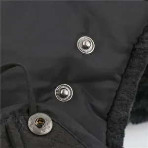 Close-up detail of winter bomber hat with metal snap buttons and thick plush fleece trim.