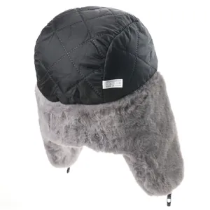 Close-up detail of winter trapper hat with quilted shell and soft grey faux fur ear flaps.