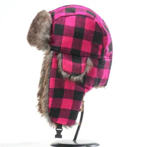 Detailed view of the pink and black plaid ushanka hat with warm faux fur ear flaps.
