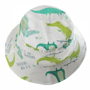 Close-up detail of white cotton children bucket hat featuring cute cartoon crocodile print.
